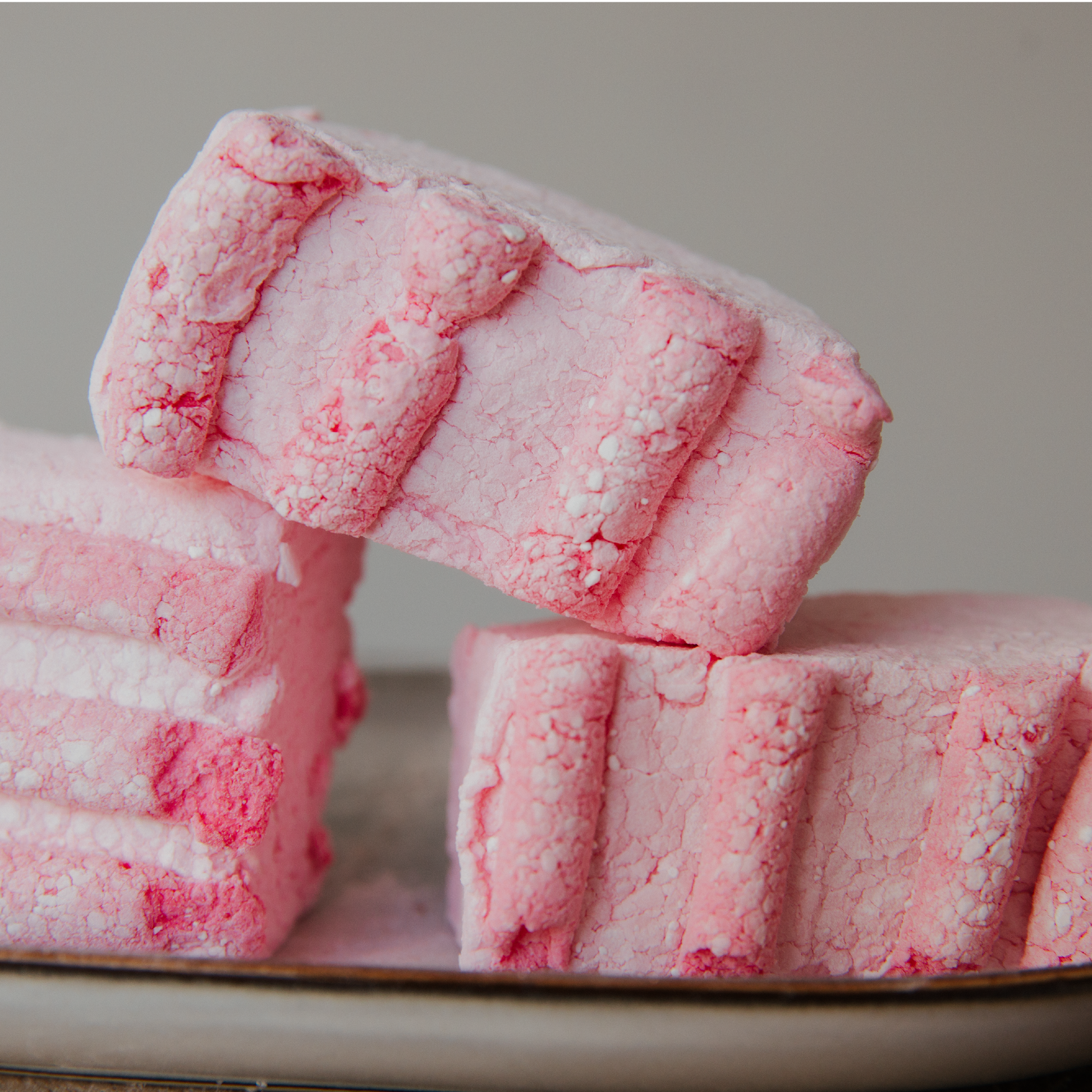Pink textured marshmallows stacked on a neutral background
