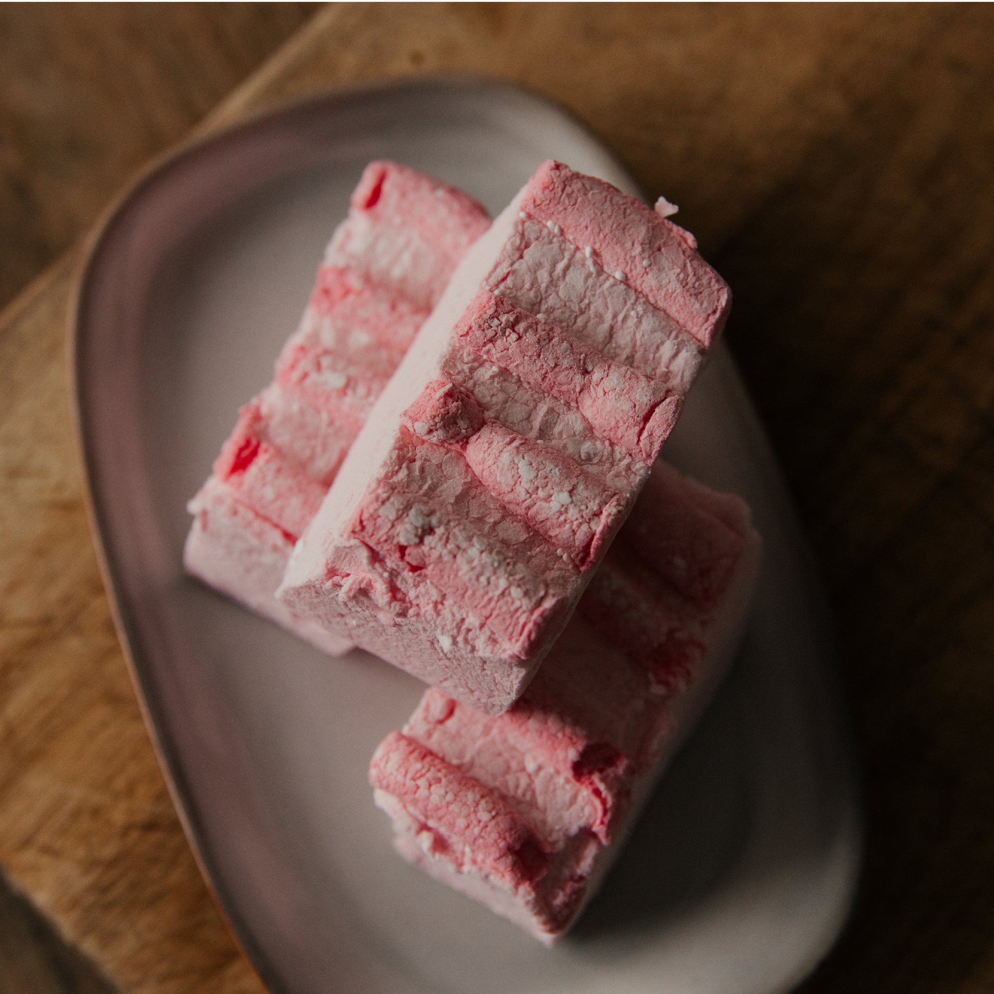 Pink candyfloss marshmallows on a plate with a wooden background