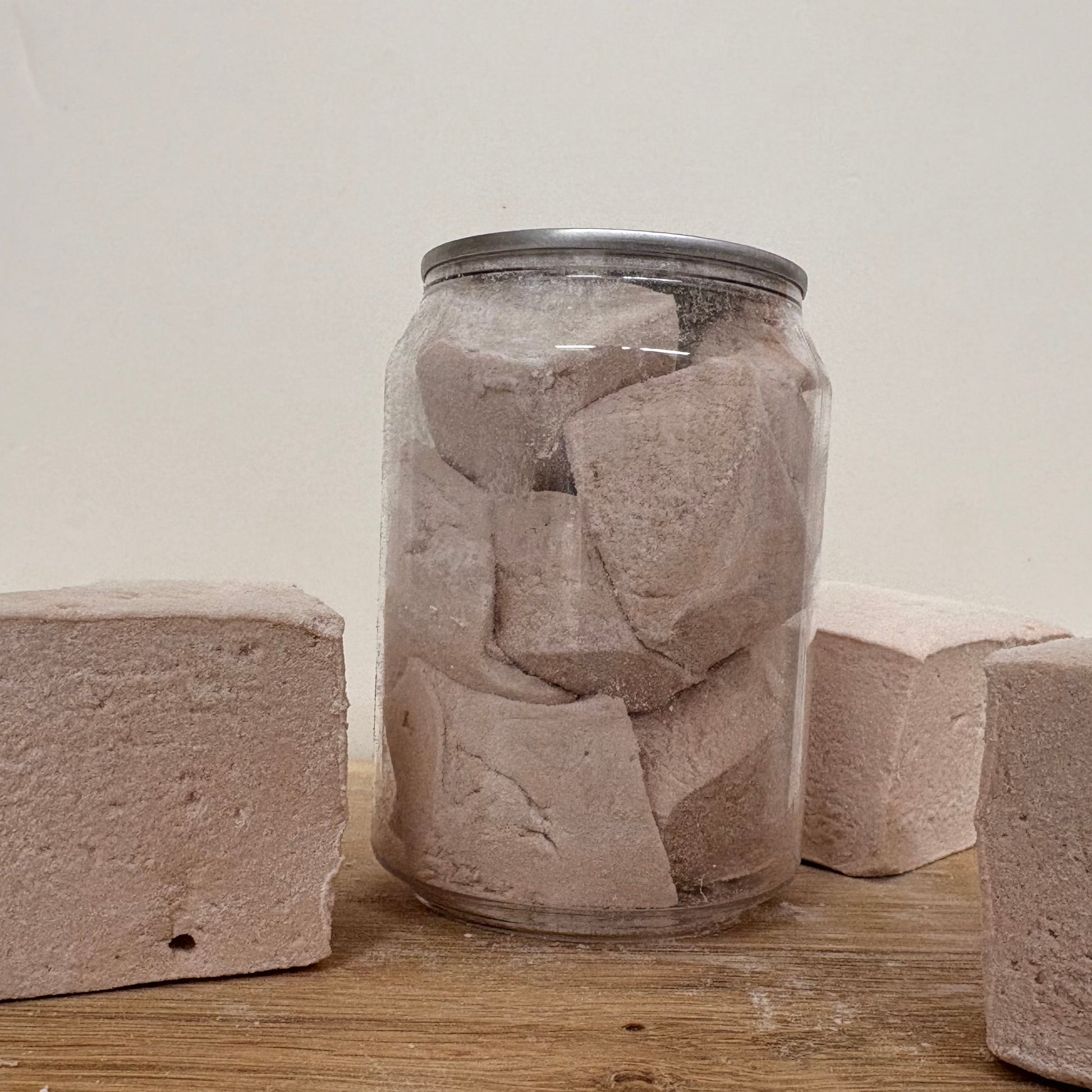 Jar filled with Scousemallow blocks on a wooden surface with more Scousemallows around.